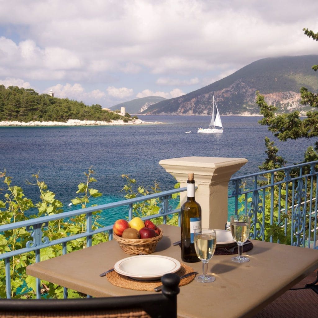 Balcony table with wine overlooking sailboats in Fiskardo bay
