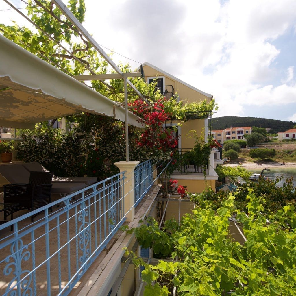 Balcony walkway with blue railing and bougainvillea overlooking Fiskardo village Kefalonia